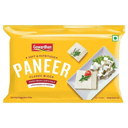 Cubes of fresh paneer on a wooden board, ready for cooking.