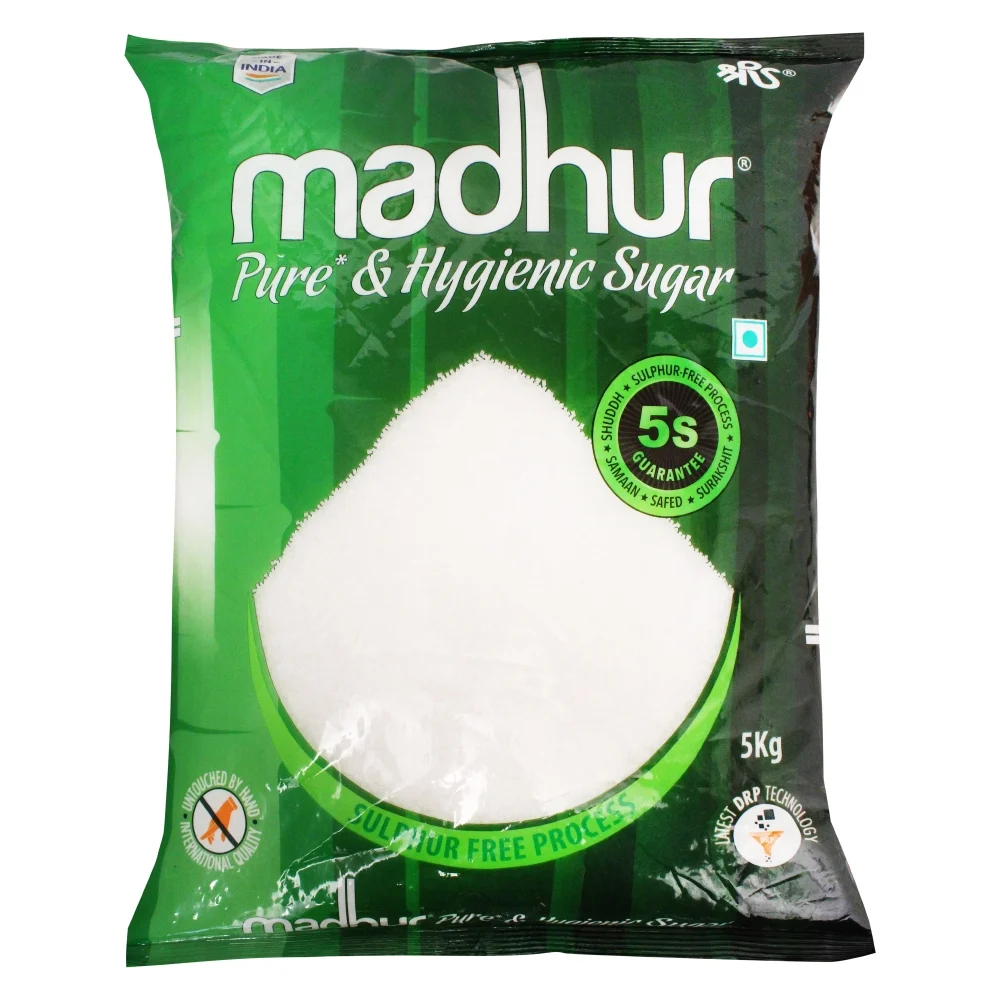 White granulated sugar in a bowl with sugar crystals scattered on a wooden surface