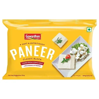 Fresh paneer cubes on a wooden plate with herbs and spices.