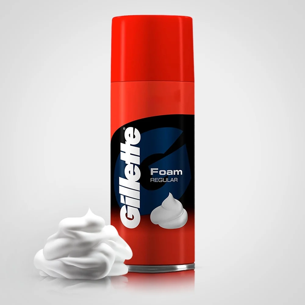 Can of shaving foam on a bathroom counter with a razor and towel nearby